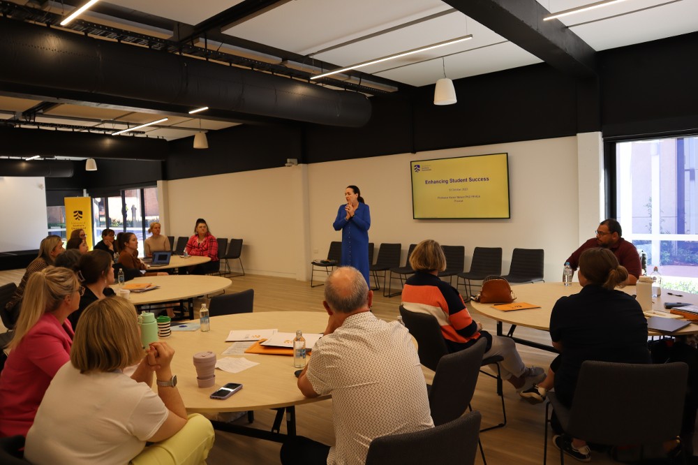 Day One of UniSQ and CUC. Groups of 4 are sitting at tables and listening to a speaker who is presenting information on enriching student success.