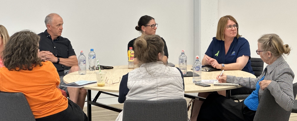 Day Two of CUC and UniSQ partnership. A table of eight are listening and taking notes on a presentation.